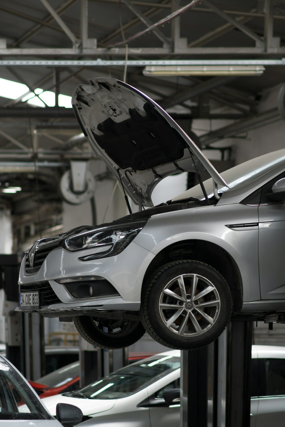 Auto argentata su un ponte sollevatore in un'officina meccanica.