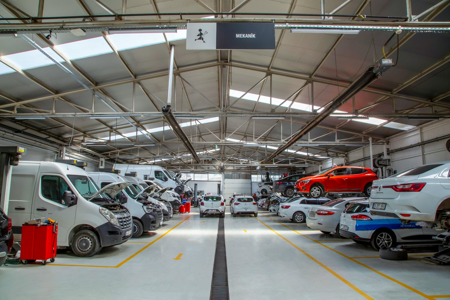Meccanici che lavorano su auto e furgoni in un'officina pulita.